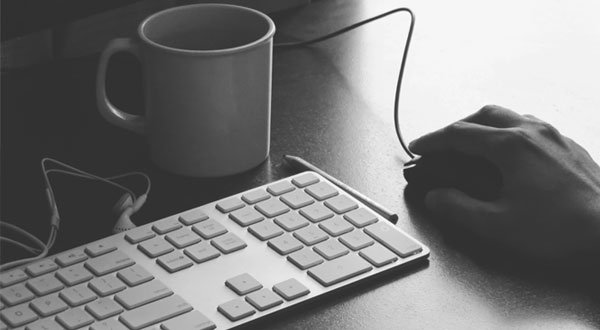 Tastiera, tazza e mouse su una scrivania di lavoro